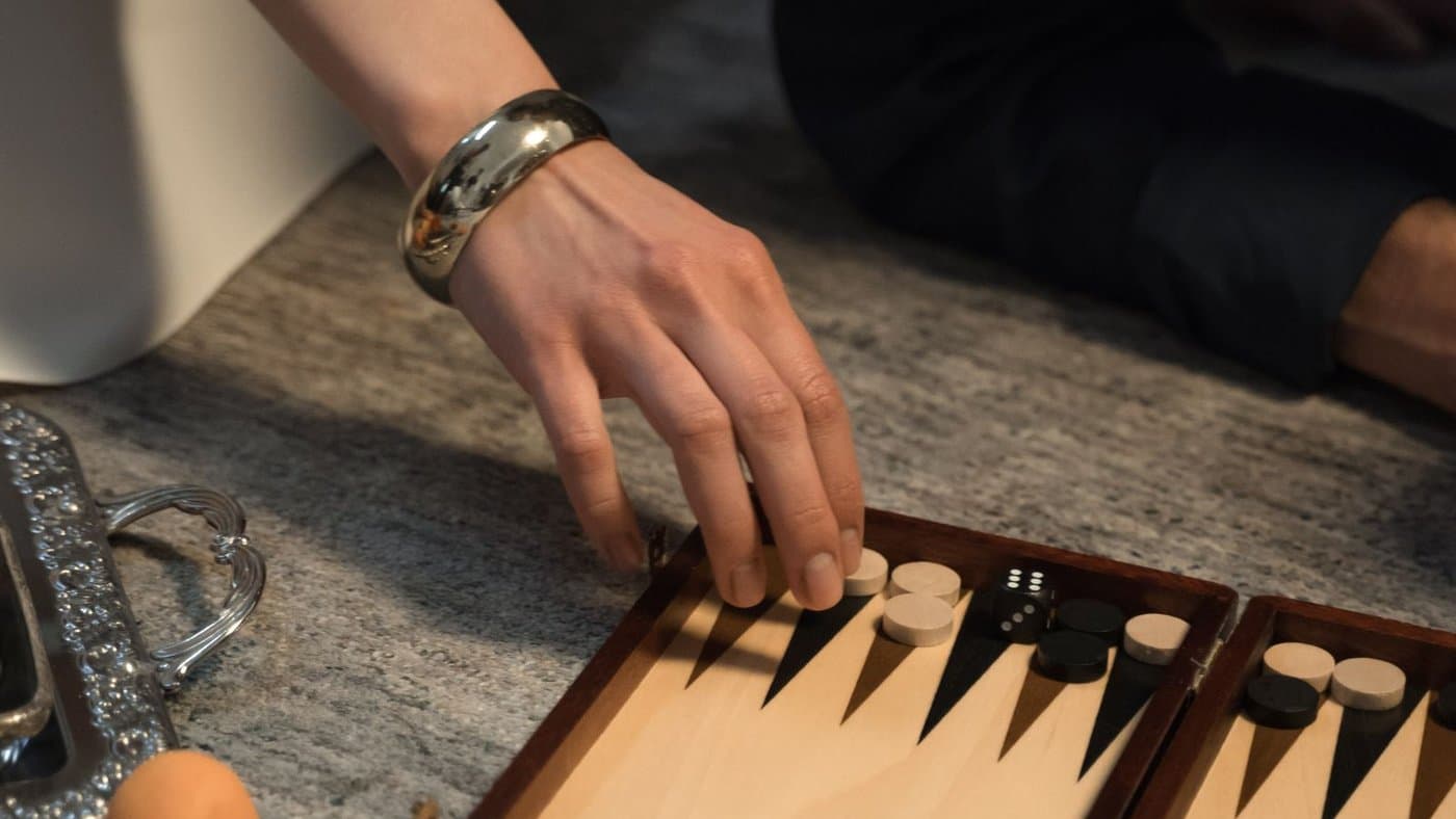 A hand placing a checker on a classic backgammon board.