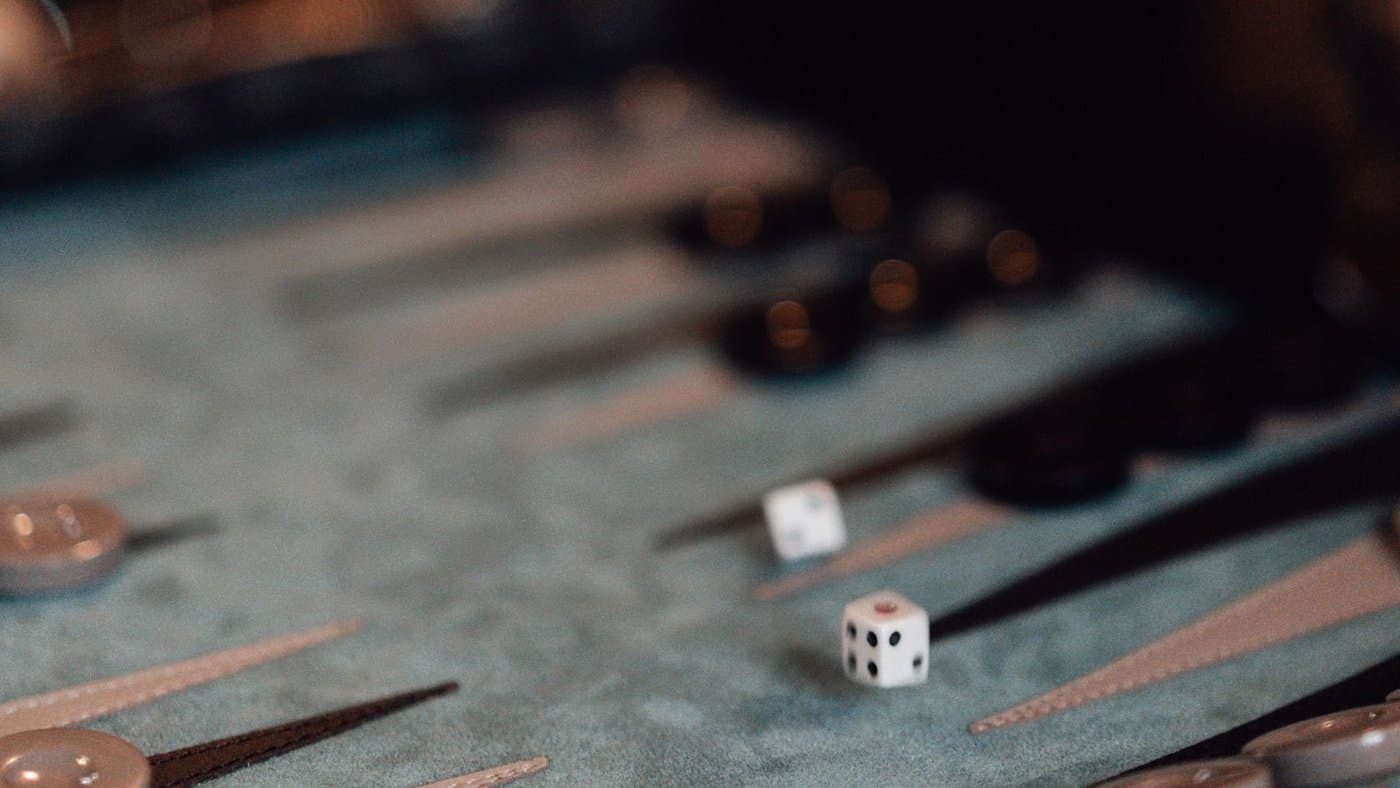 A hand mid-throw, dice landing on a backgammon board.