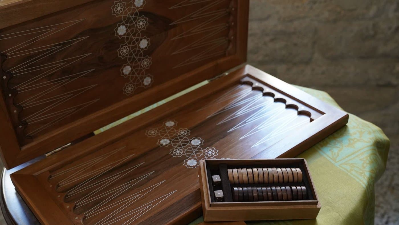 An ornate wooden backgammon set with mother-of-pearl inlay, opened and ready to play.